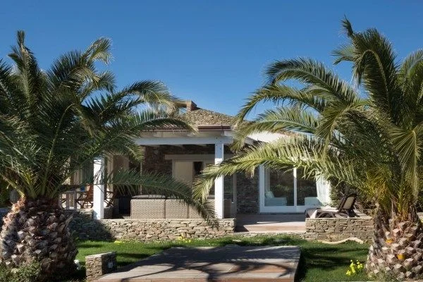 La facciata in pietra della villa e il giardino con palme